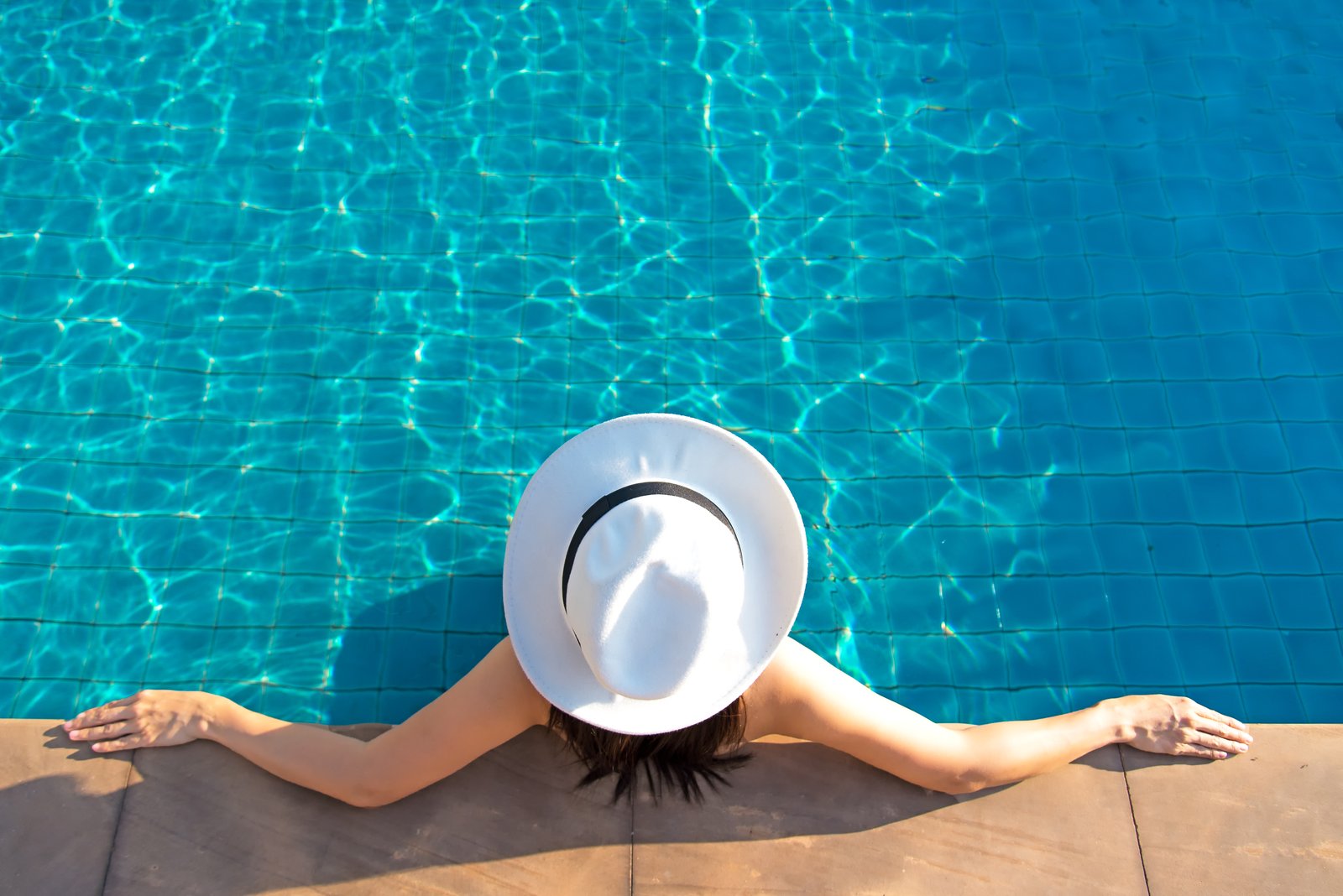 Frau entspannt am Rand eines blauen Pools